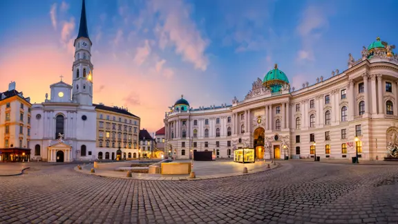 City centre of Vienna at sunset, with historic buildings bathed in warm golden light and a colorful sky overhead.