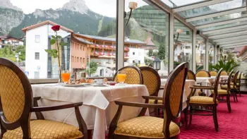 A table laid for breakfast in the hotel's dining room, with a view from the windows of the vast Dolomite mountains