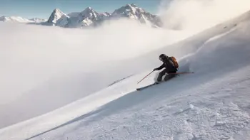 A lone skier rushes down a slope in Murren, kicking up powdered snow as they descend.