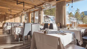 A look at the hotel's restaurant, with prepared tables and a view from the windows of the vast snowy mountains and clear sky.
